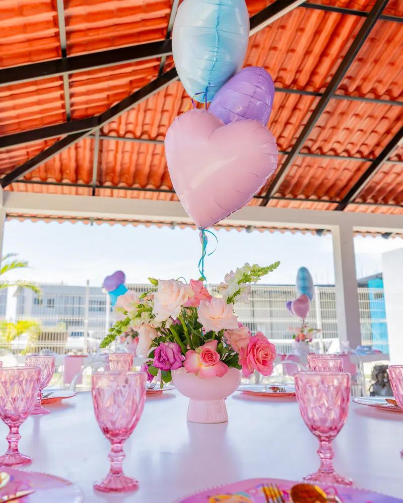 Mesa con copas rosas y globos de corazón bajo la palapa